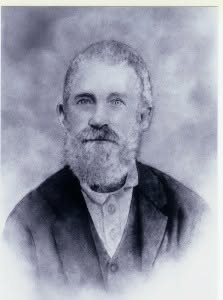 Black and white portrait of an older man with a beard, wearing a formal coat and collared shirt, set against a soft background.