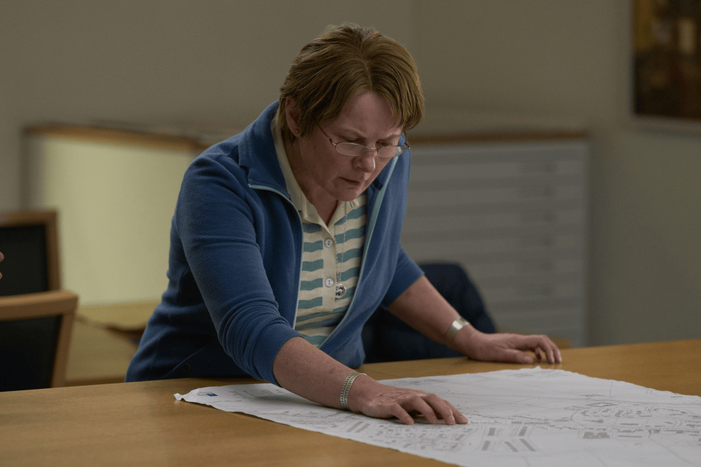 A woman studying a detailed blueprint on a table, appearing focused and engaged.